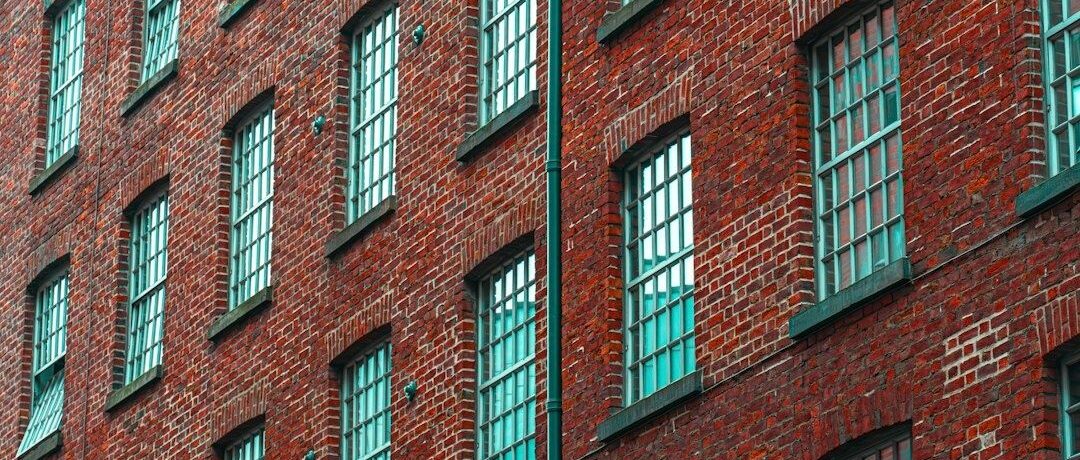 Röd tegelindustribyggnad med många turkosa spröjsade fönster