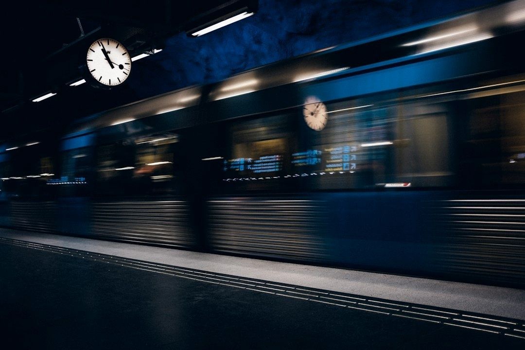 Ett snabbt passerande tåg på en mörk station med stationsklocka